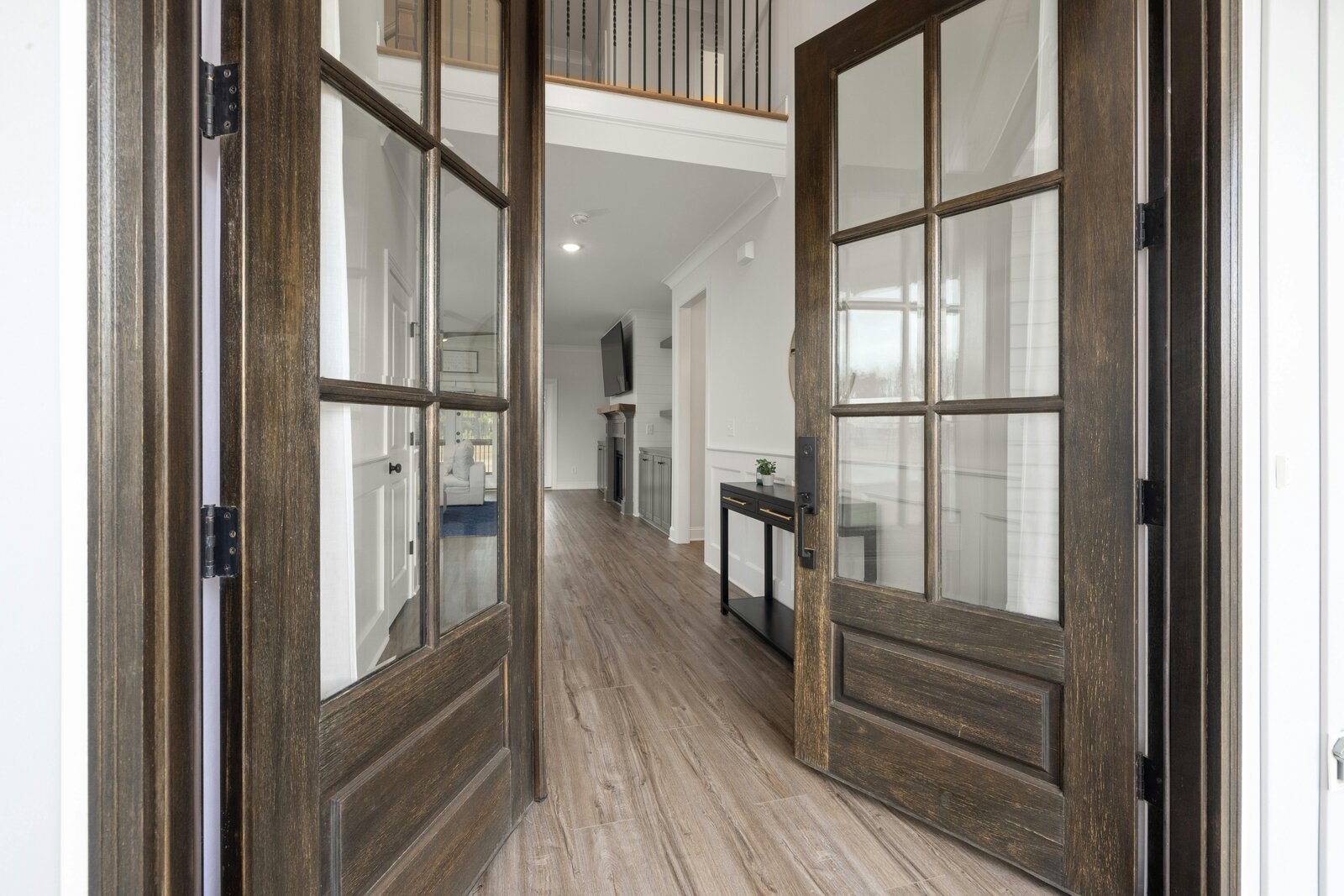 Open French doors looking into a brightly lit interior with wood floors and white walls