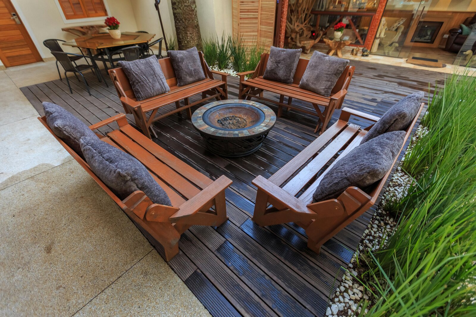 Outdoor wooden deck with bench seating arranged around a stone fire pit